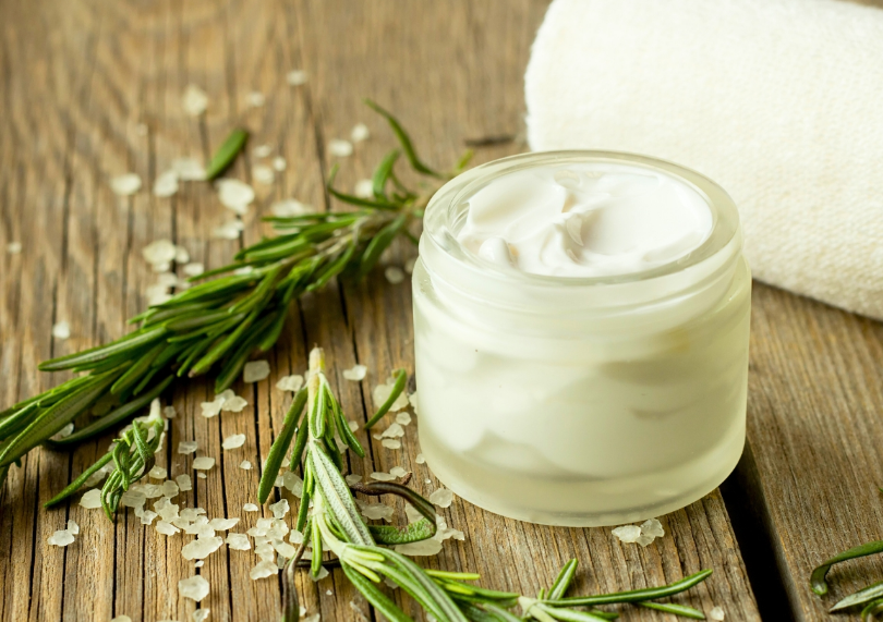 Face cream and rosemary on table